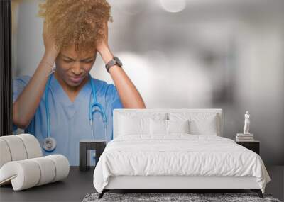 Young african american doctor woman over isolated background suffering from headache desperate and stressed because pain and migraine. Hands on head. Wall mural