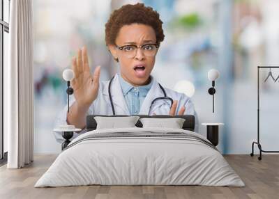 Young african american doctor woman wearing medical coat over isolated background afraid and terrified with fear expression stop gesture with hands, shouting in shock. Panic concept. Wall mural