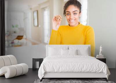 Young african american girl eating chocolate chips cookies as sweet snack with a happy face standing and smiling with a confident smile showing teeth Wall mural