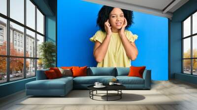 Young african american girl wearing casual clothes covering ears with fingers with annoyed expression for the noise of loud music. deaf concept. Wall mural