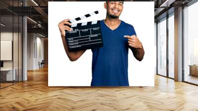 Young african american man holding video film clapboard smiling happy pointing with hand and finger Wall mural