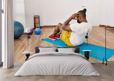 Young african american man on back view training abs exercise at sport center Wall mural