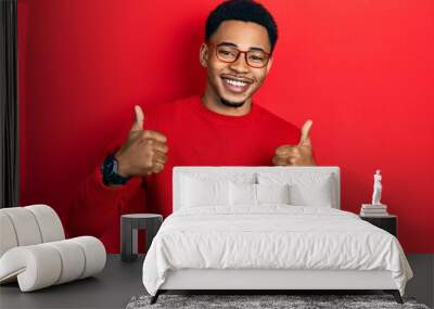 young african american man wearing casual clothes and glasses success sign doing positive gesture wi Wall mural