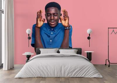 Young african american man wearing casual clothes gesturing finger crossed smiling with hope and eyes closed. luck and superstitious concept. Wall mural