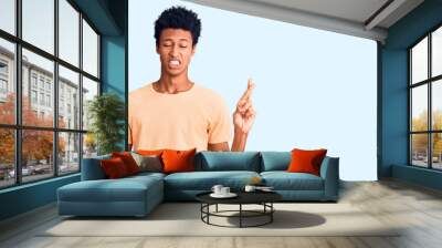 Young african american man wearing casual clothes gesturing finger crossed smiling with hope and eyes closed. luck and superstitious concept. Wall mural