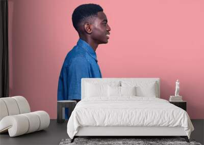 Young african american man wearing casual clothes looking to side, relax profile pose with natural face and confident smile. Wall mural