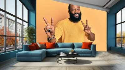 Young african american man wearing casual clothes smiling looking to the camera showing fingers doing victory sign. number two. Wall mural