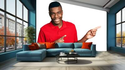 Young african american man wearing casual red t shirt smiling and looking at the camera pointing with two hands and fingers to the side. Wall mural