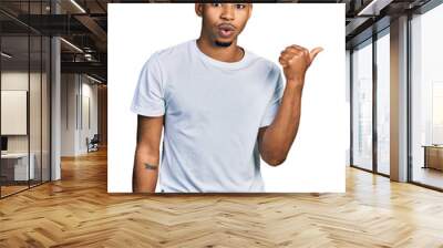 Young african american man wearing casual white t shirt surprised pointing with hand finger to the side, open mouth amazed expression. Wall mural