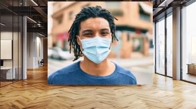 Young african american man wearing medical mask looking to the camera at street of city. Wall mural