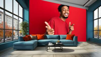 Young african american man with beard wearing casual red t shirt pointing fingers to camera with happy and funny face. good energy and vibes. Wall mural