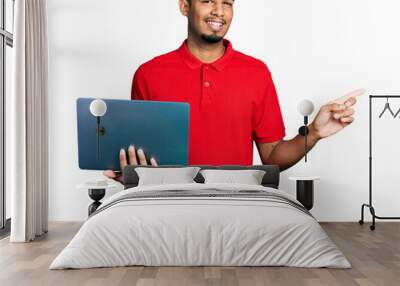 Young african american man working using computer laptop smiling happy pointing with hand and finger to the side Wall mural