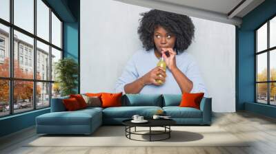 Young african american woman over grey grunge wall drinking detox green juice with a confident expression on smart face thinking serious Wall mural