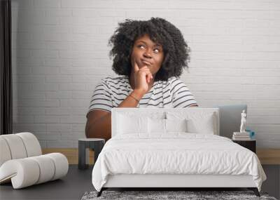 Young african american woman sitting on the table using computer laptop serious face thinking about question, very confused idea Wall mural