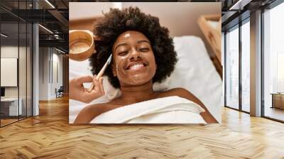 Young african american woman smiling confident having facial treatment at beauty center Wall mural