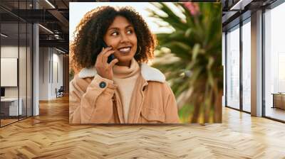 Young african american woman smiling happy talking on the smartphone at the park. Wall mural