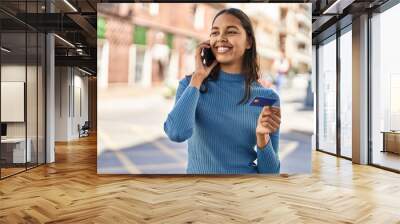 Young african american woman talking on the smartphone and using credit card at street Wall mural