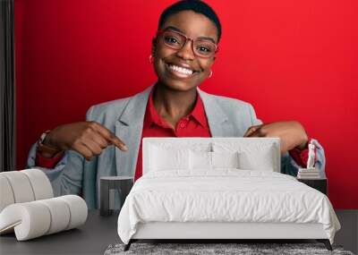 Young african american woman wearing business jacket and glasses looking confident with smile on face, pointing oneself with fingers proud and happy. Wall mural