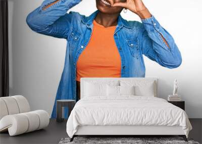 Young african american woman wearing casual clothes doing heart shape with hand and fingers smiling looking through sign Wall mural