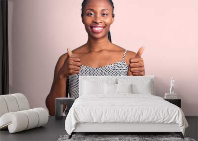 Young african american woman wearing casual clothes success sign doing positive gesture with hand, thumbs up smiling and happy. cheerful expression and winner gesture. Wall mural