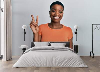 Young african american woman wearing casual orange t shirt showing and pointing up with fingers number two while smiling confident and happy. Wall mural