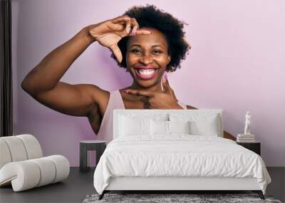 Young african american woman wearing casual sleeveless t shirt smiling making frame with hands and fingers with happy face. creativity and photography concept. Wall mural