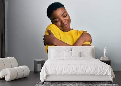 Young african american woman wearing casual yellow t shirt hugging oneself happy and positive, smiling confident. self love and self care Wall mural