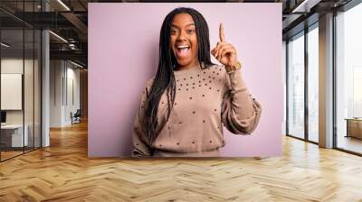 Young african american woman wearing fashion sweater over pink isolated background pointing finger up with successful idea. Exited and happy. Number one. Wall mural