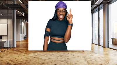 Young african american woman wearing sportswear pointing finger up with successful idea. exited and happy. number one. Wall mural