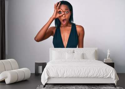 Young african american woman wearing swimsuit doing ok gesture shocked with surprised face, eye looking through fingers. unbelieving expression. Wall mural