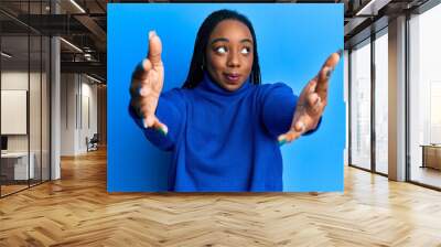 Young african american woman with arms stretched hug gesture smiling looking to the side and staring away thinking. Wall mural