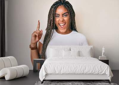 Young african american woman with braids wearing casual white tshirt pointing finger up with successful idea. exited and happy. number one. Wall mural