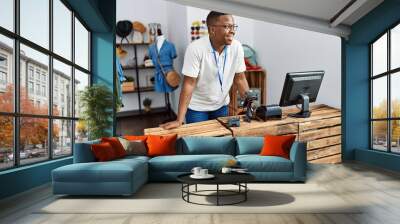 Young african man working as shop assistance at retail shop Wall mural