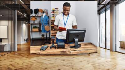 Young african man working as shop assistance using touchpad at retail shop Wall mural