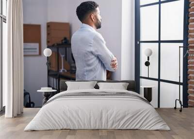 Young arab man business worker looking throw the window with arms crossed gesture at office Wall mural