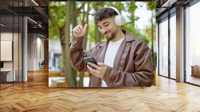 Young arab man smiling confident listening to music and dancing at park Wall mural