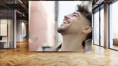 Young arab man smiling confident looking to the sky at street Wall mural