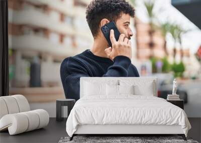 Young arab man smiling confident talking on the smartphone at street Wall mural