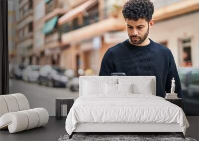 Young arab man using smartphone at street Wall mural