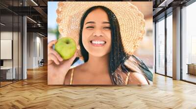 Young asian girl smiling happy at the city eating a healthy green apple Wall mural