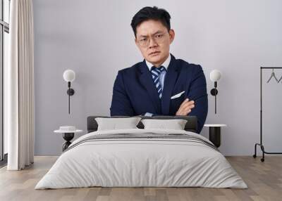 Young asian man wearing business suit and tie skeptic and nervous, disapproving expression on face with crossed arms. negative person. Wall mural