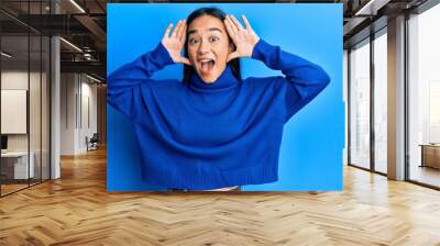 Young asian woman wearing casual winter sweater smiling cheerful playing peek a boo with hands showing face. surprised and exited Wall mural