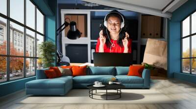 Young asian woman working at the office with laptop at night gesturing finger crossed smiling with hope and eyes closed. luck and superstitious concept. Wall mural