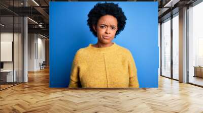 Young beautiful African American afro woman with curly hair wearing yellow casual sweater skeptic and nervous, frowning upset because of problem. Negative person. Wall mural