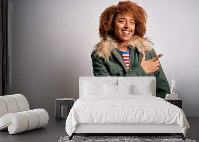 Young beautiful African American woman with curly hair wearing green casual winter coat cheerful with a smile of face pointing with hand and finger up to the side with happy and natural expression Wall mural