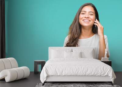 Young beautiful arab woman talking on the phone over isolated background with a happy face standing and smiling with a confident smile showing teeth Wall mural