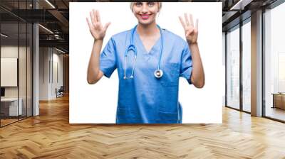 Young beautiful blonde doctor surgeon nurse woman over isolated background showing and pointing up with fingers number nine while smiling confident and happy. Wall mural