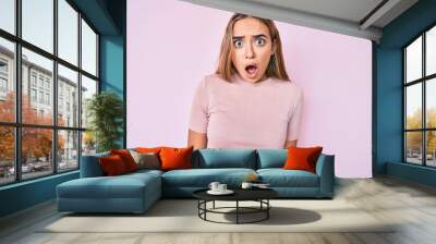 Young beautiful blonde woman wearing casual clothes scared and amazed with open mouth for surprise, disbelief face Wall mural