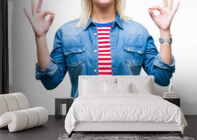 Young beautiful blonde woman wearing denim jacket over isolated background relax and smiling with eyes closed doing meditation gesture with fingers. Yoga concept. Wall mural