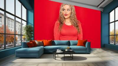 Young beautiful blonde woman wearing red casual t-shirt standing over isolated background smiling looking to the side and staring away thinking. Wall mural